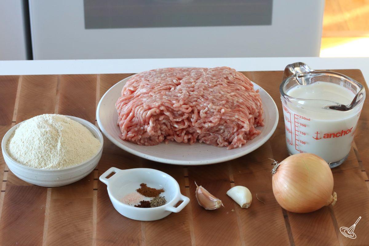 A plate of ground pork with a side dish of breadcrumbs and a cup of milk.