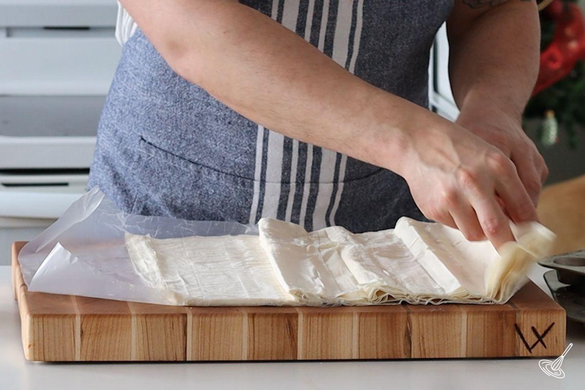 Someone unfolding a roll of phyllo pastry.