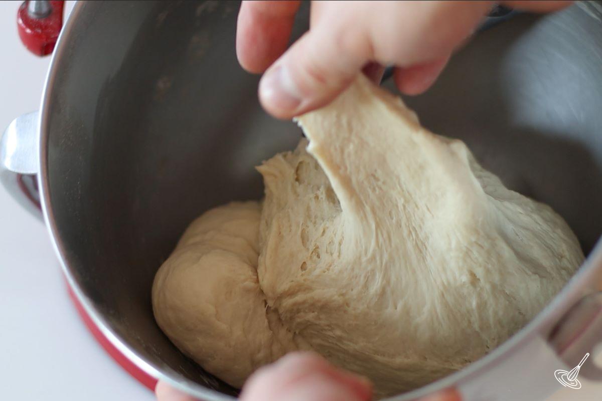 Someone using their fingers to test the elasticity of the bread dough.
