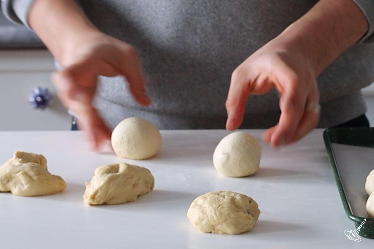 Someone shaping pieces of dough into ball.