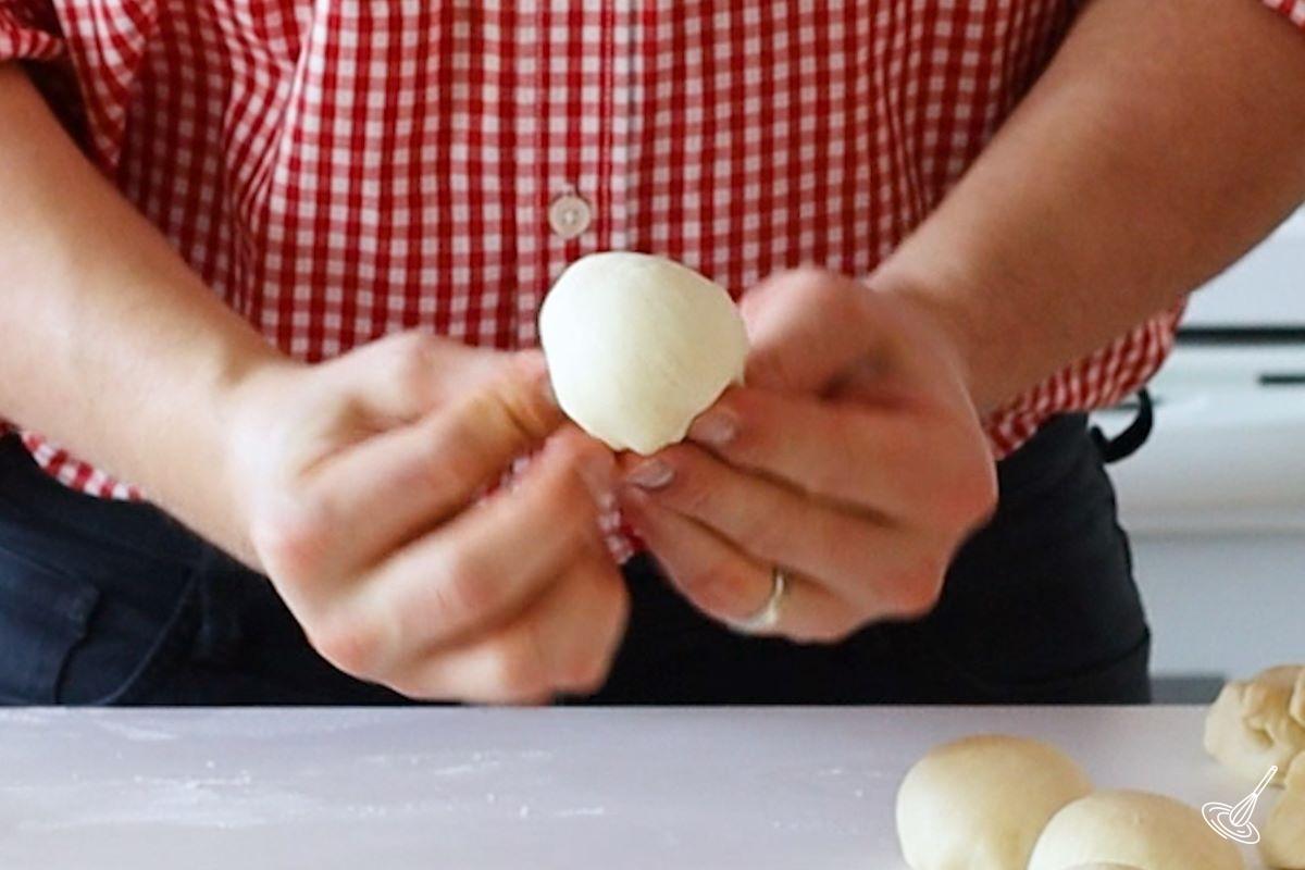 Someone using their hands to shape a ball of dough. 