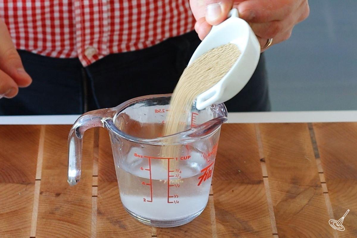 Yeast being added to a measuring cup of water.