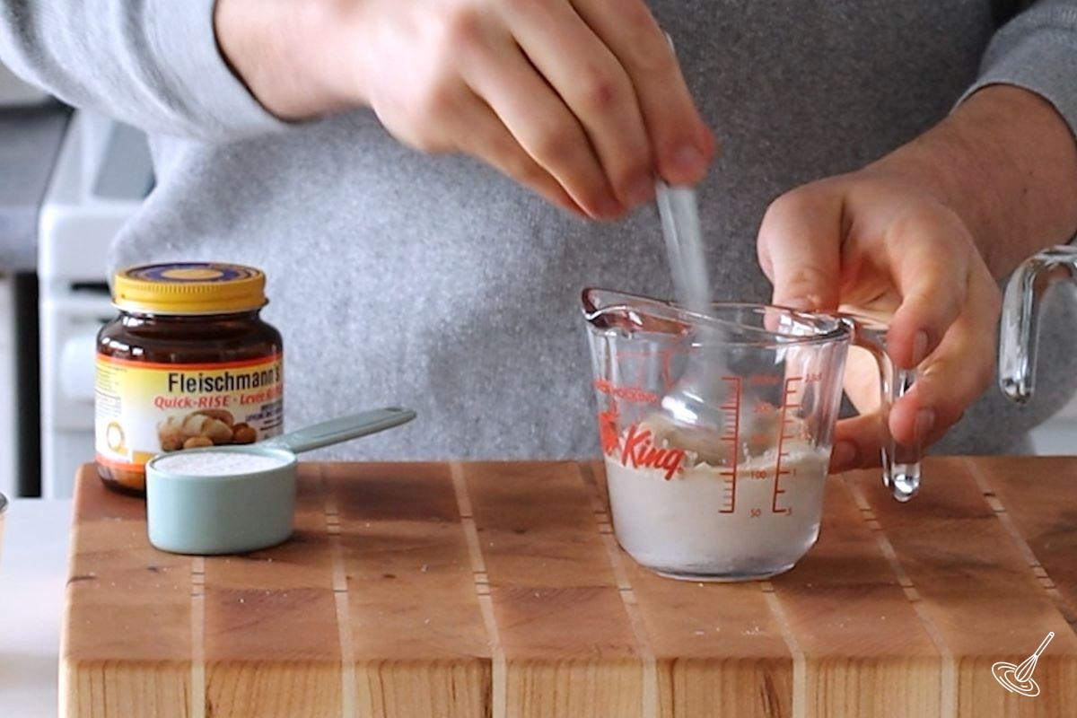 Someone mixing together a yeast and water mixture.