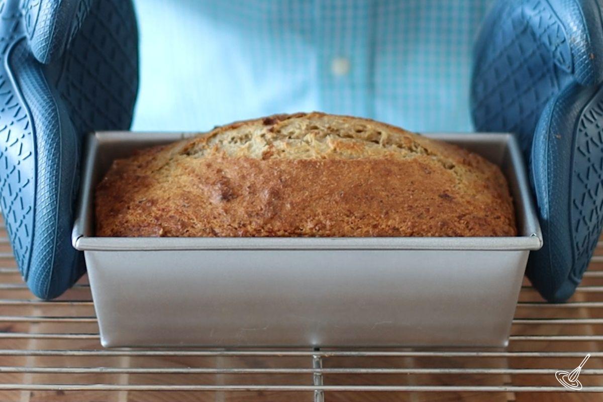 Someone placing a baked Cottage Cheese Banana Bread on a cooling rack.