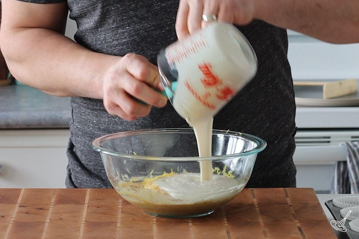Someone pouring milk into a bowl with other wet ingredients.