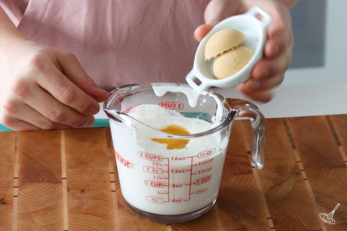 Someone adding brown sugar to a mixture of cottage cheese.