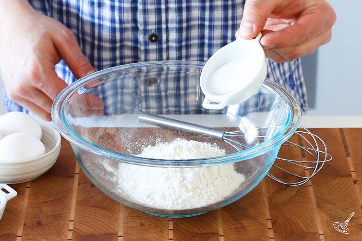 Someone combining dry ingredients into a large bowl. 