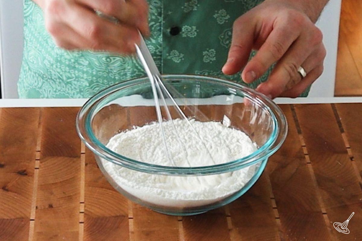 Someone whisking a flour mixture for Pâte à Crêpes in a bowl.