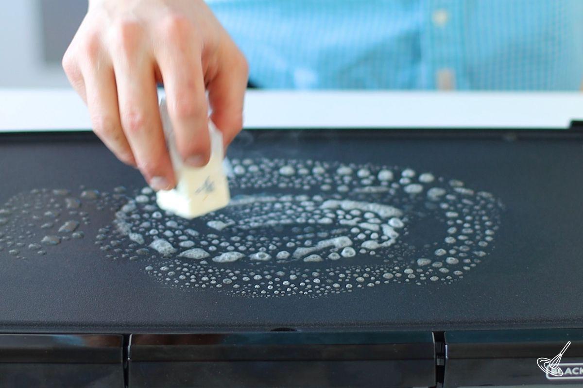 Someone melting butter on a hot griddle.