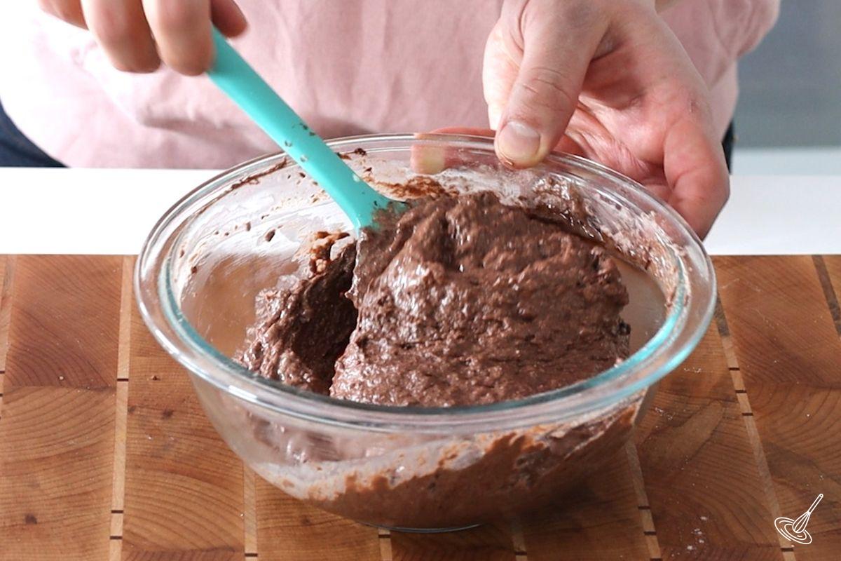 Someone using a rubber spatula to mix a Chocolate Cottage Cheese Waffles batter.