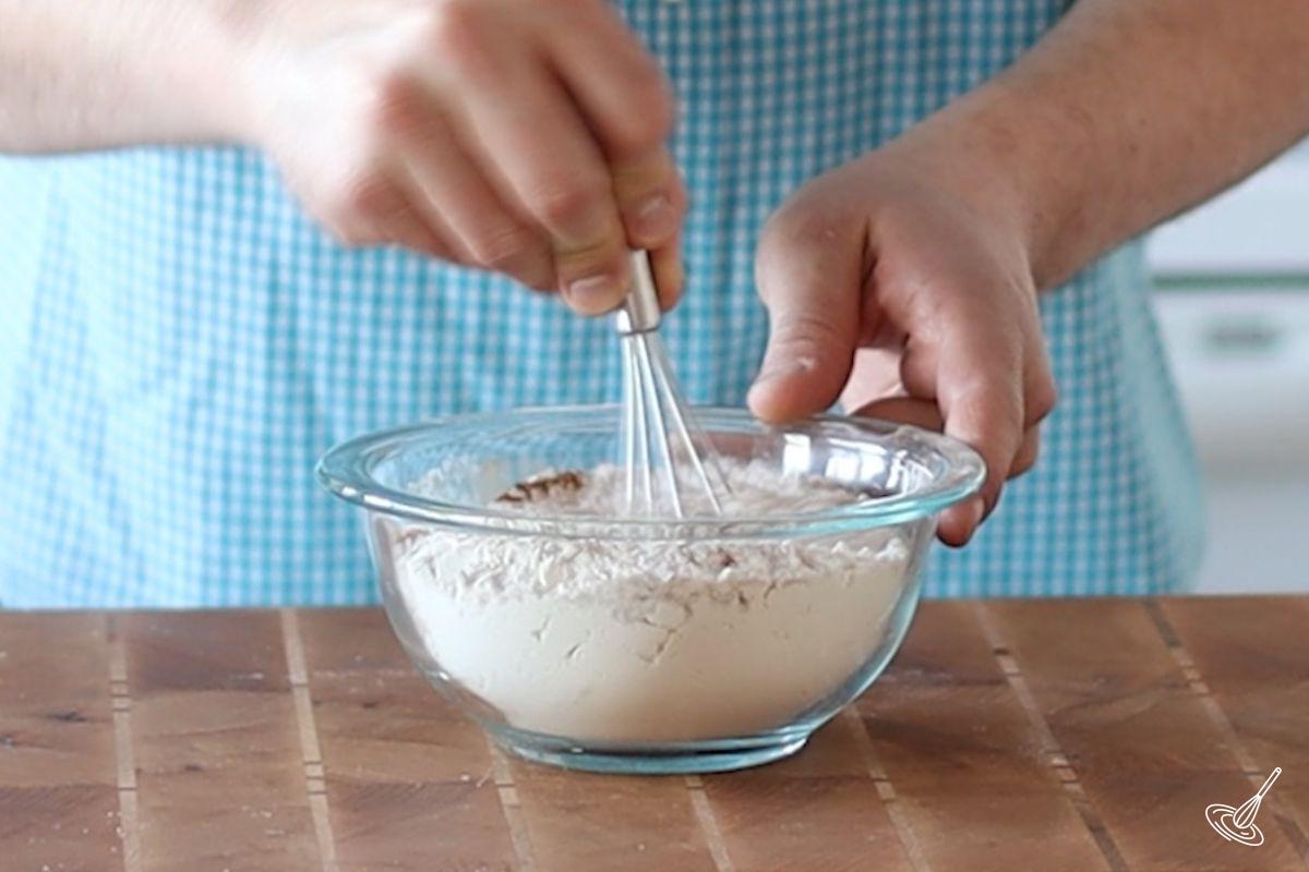 Someone whisking a flour mixture in a bowl.