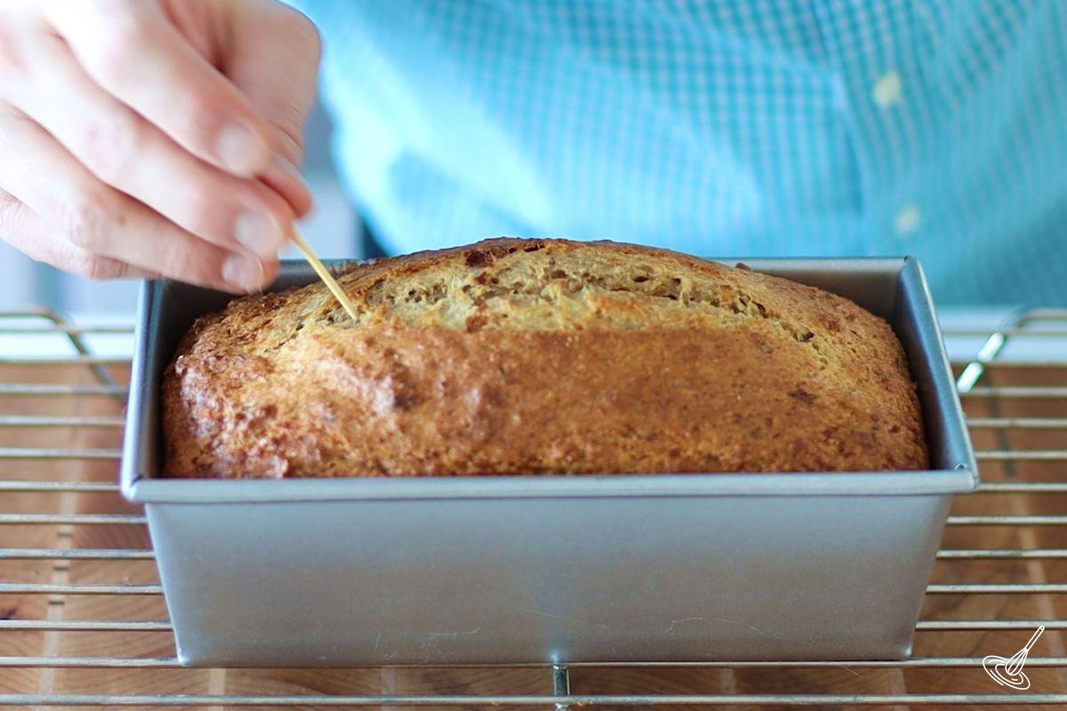 Someone using a toothpick to check the doneness of Cottage Cheese Banana Bread.