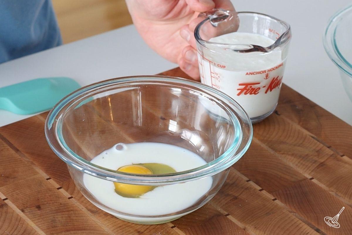 A small glass bowl containing milk and egg. 