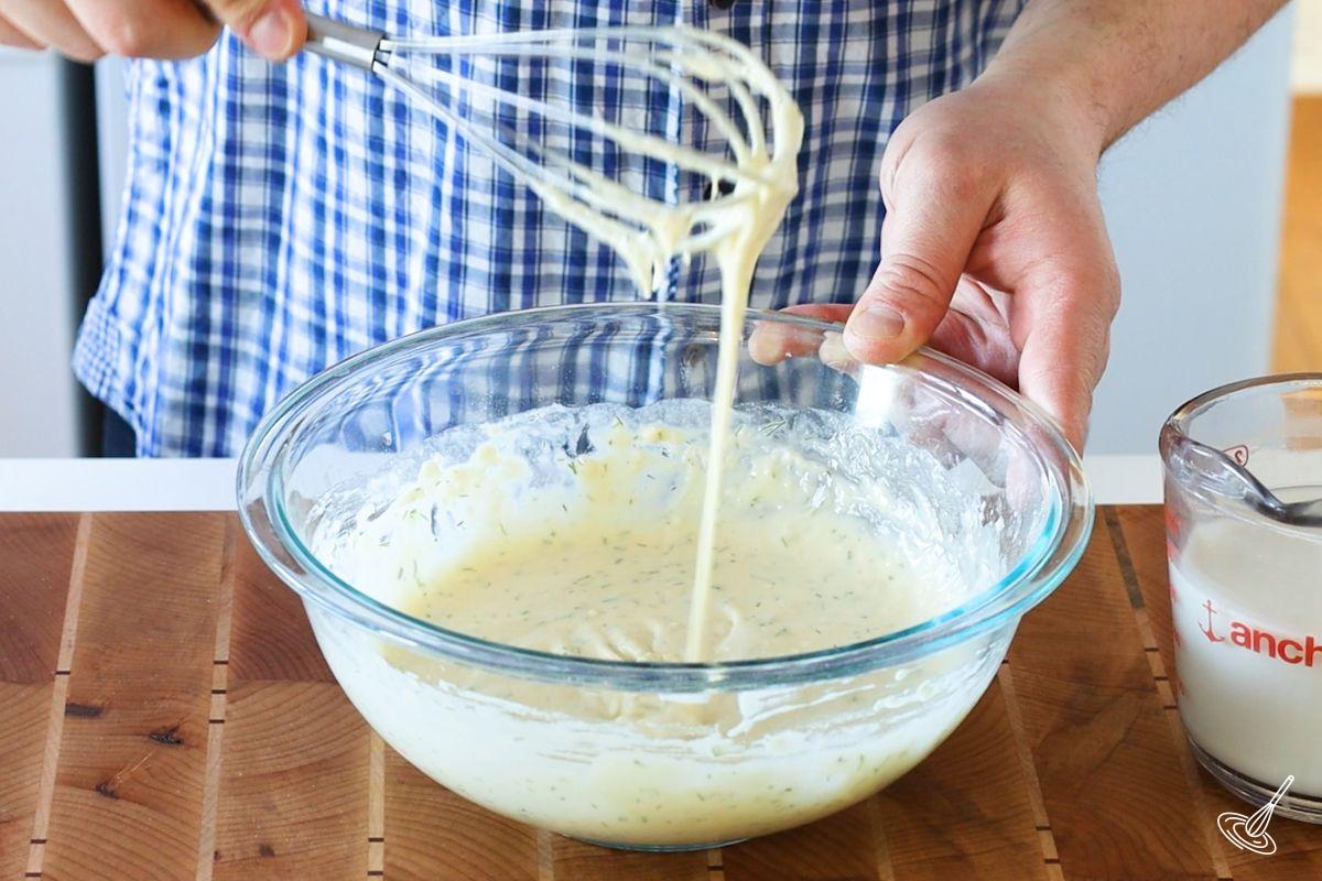 Someone using a whisk to mix Dill French Crêpes batter.
