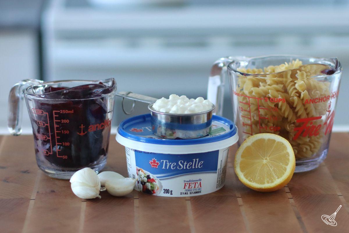 Ingredients on a board including roasted beets, feta, and pasta.
