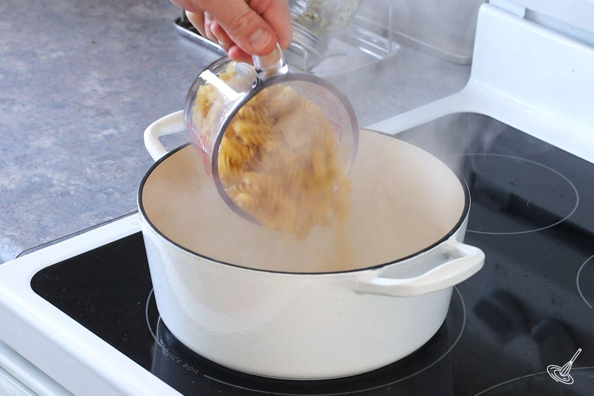 Someone adding pasta to a pot of boiling water.