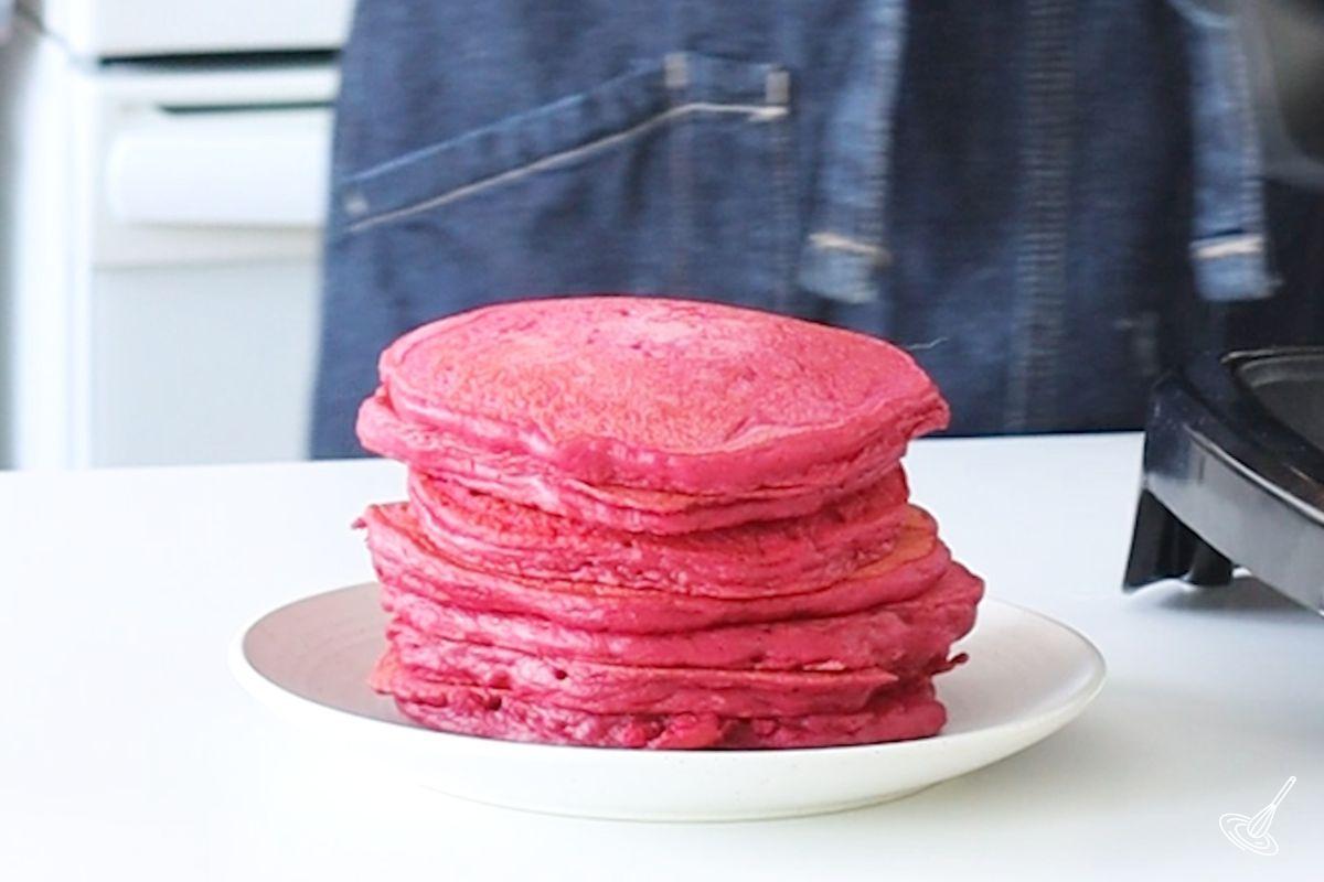 A stack of pink beet pancakes on a white plate.