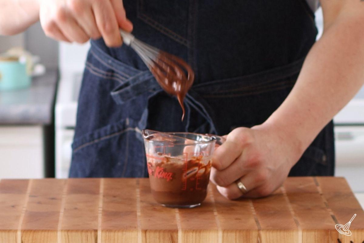Someone using a small whisk to make the chocolate filling. 
