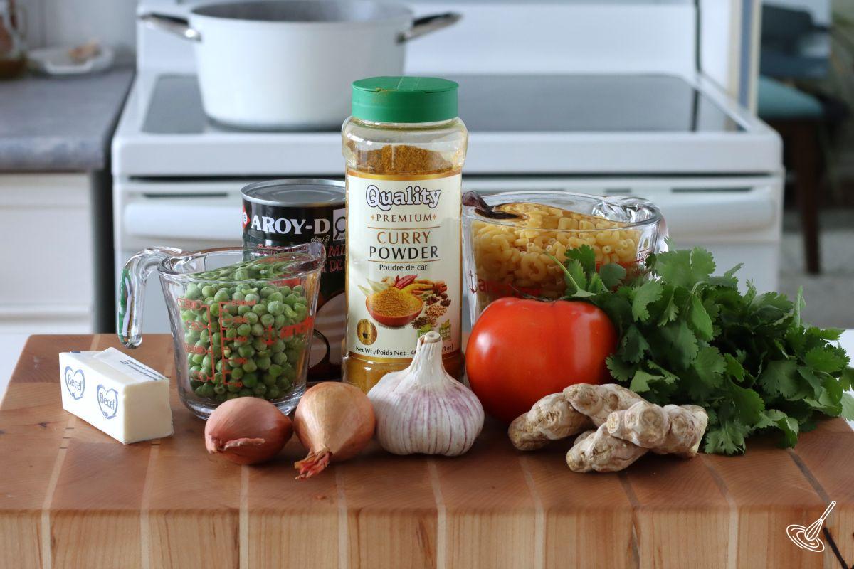 Ingredients on a cutting board including curry powder, pasta, and vegetables. 
