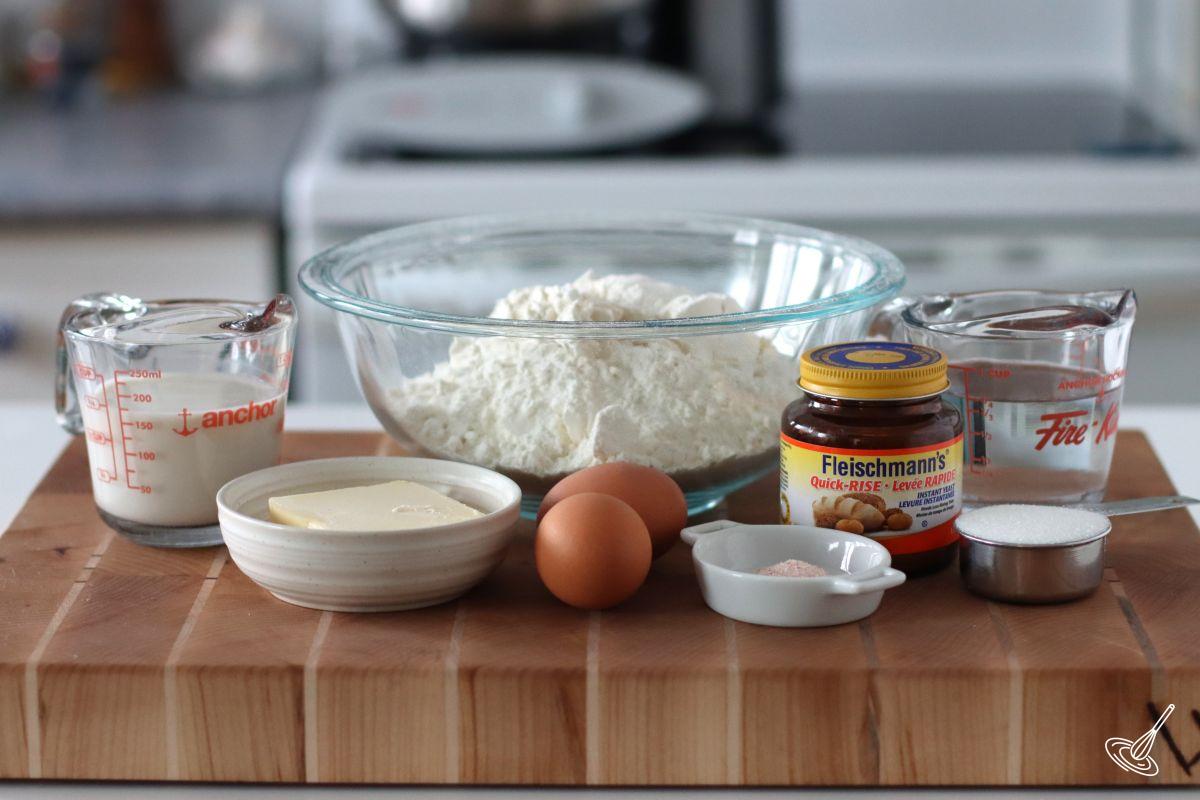 Ingredients on a cutting board, including flour, butter, milk, and yeast.
