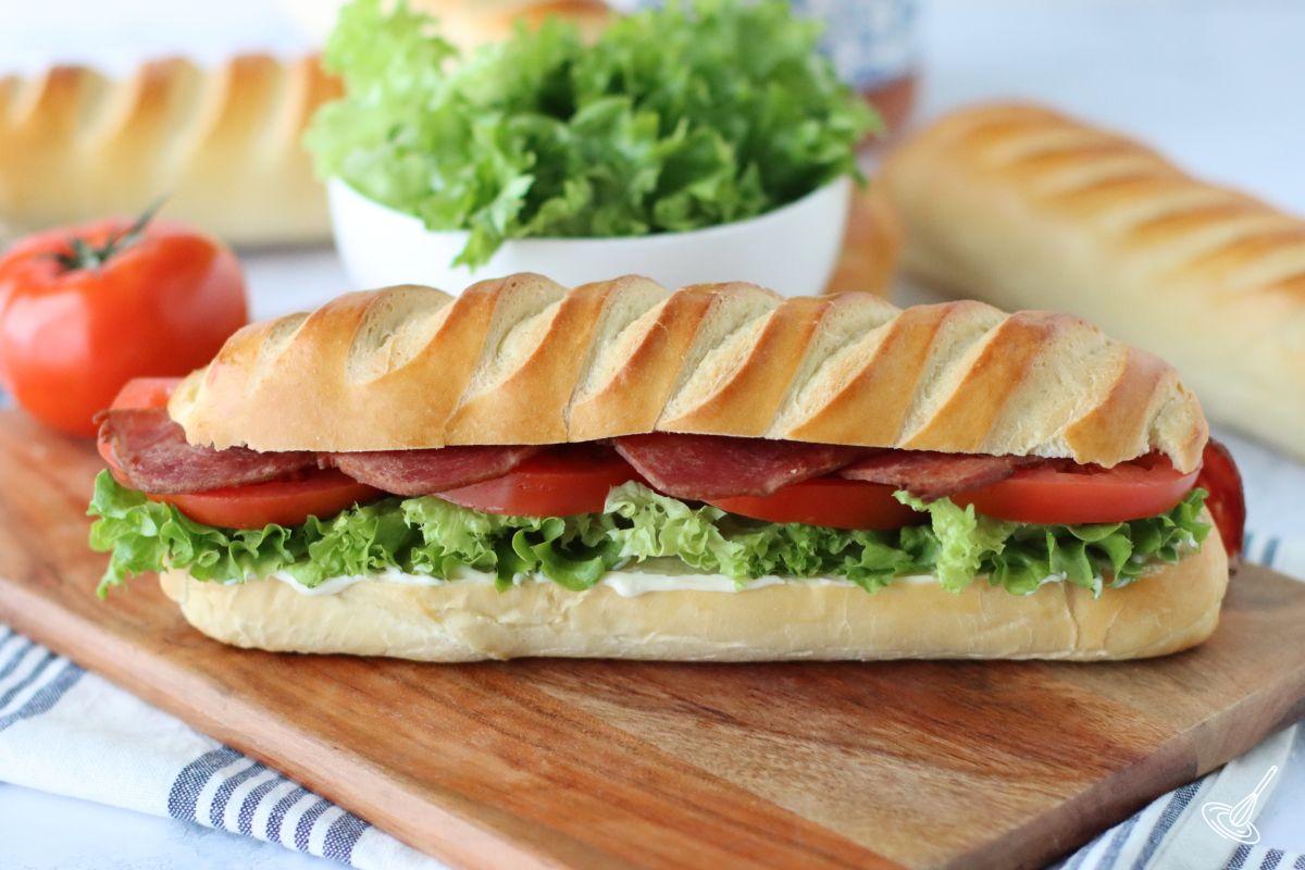 A BLT sandwich made with a brioche sub roll on a wooden board. 