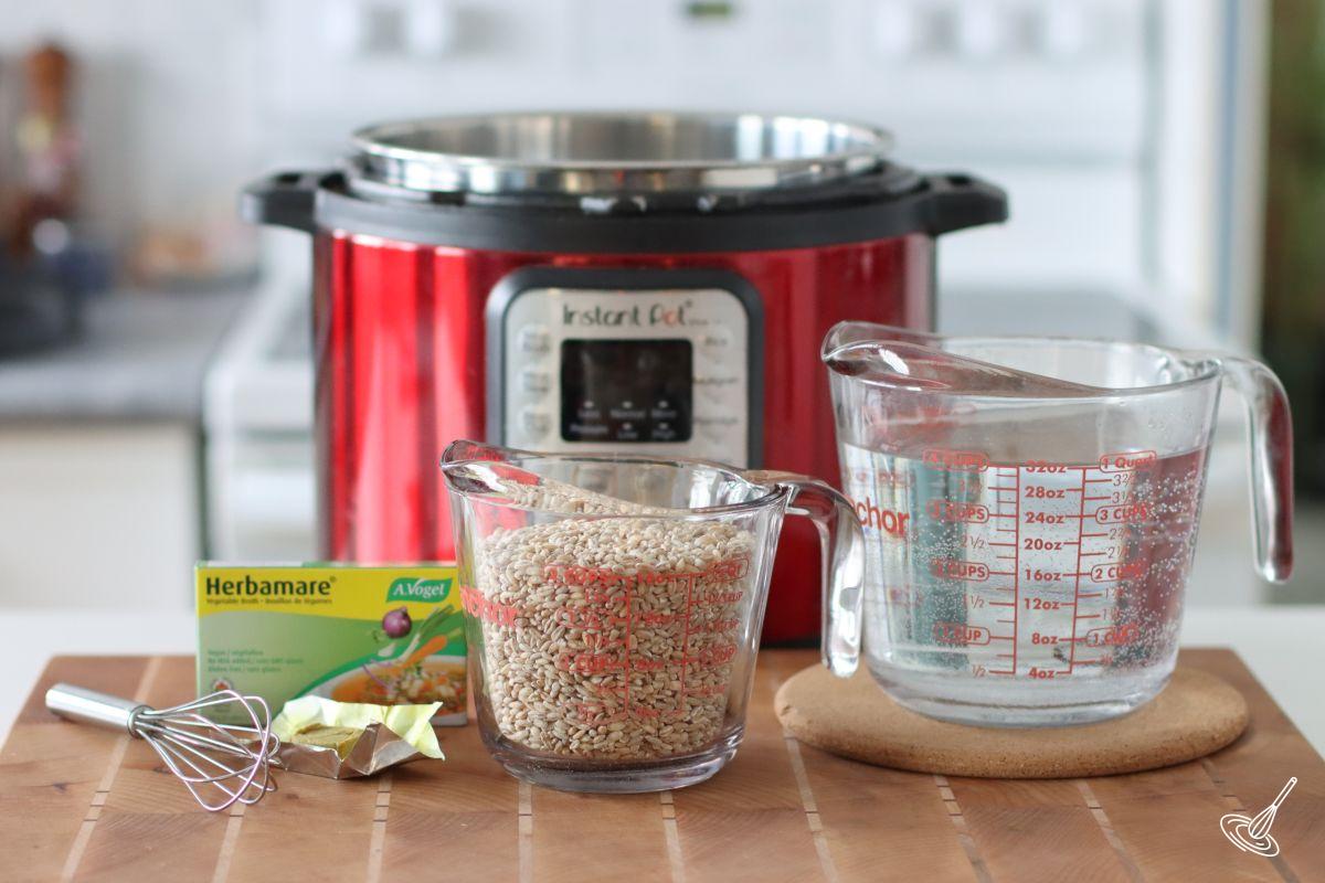 A measuring cup of pot barley beside a measuring cup of water. 