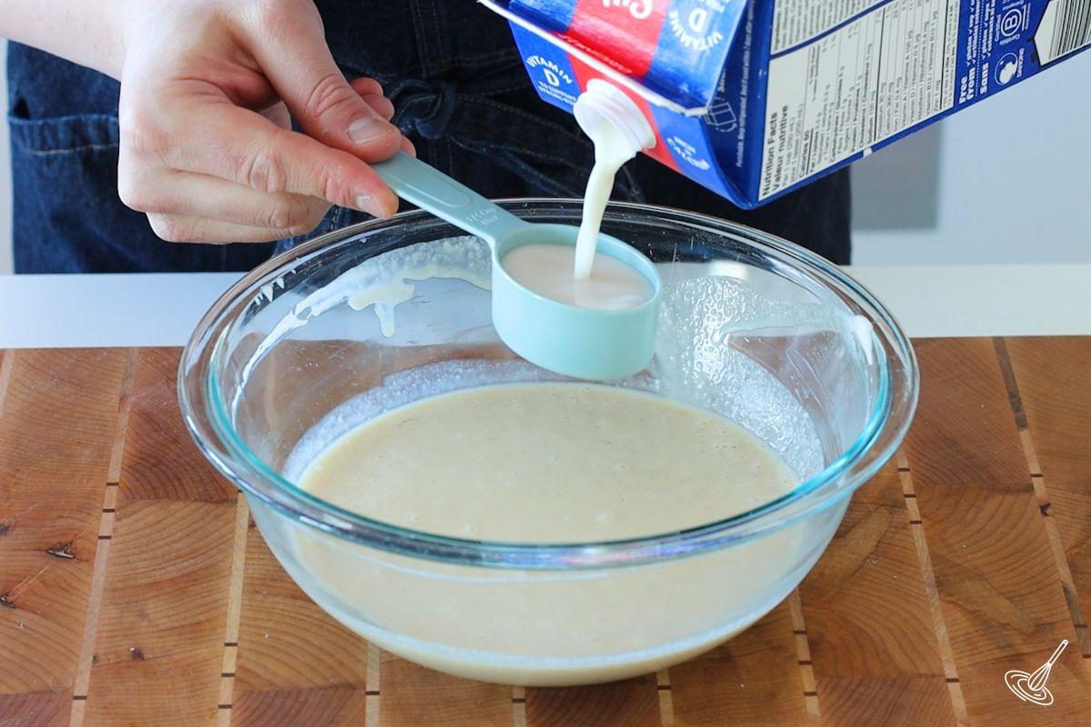 Someone using a measuring cup to measure milk.