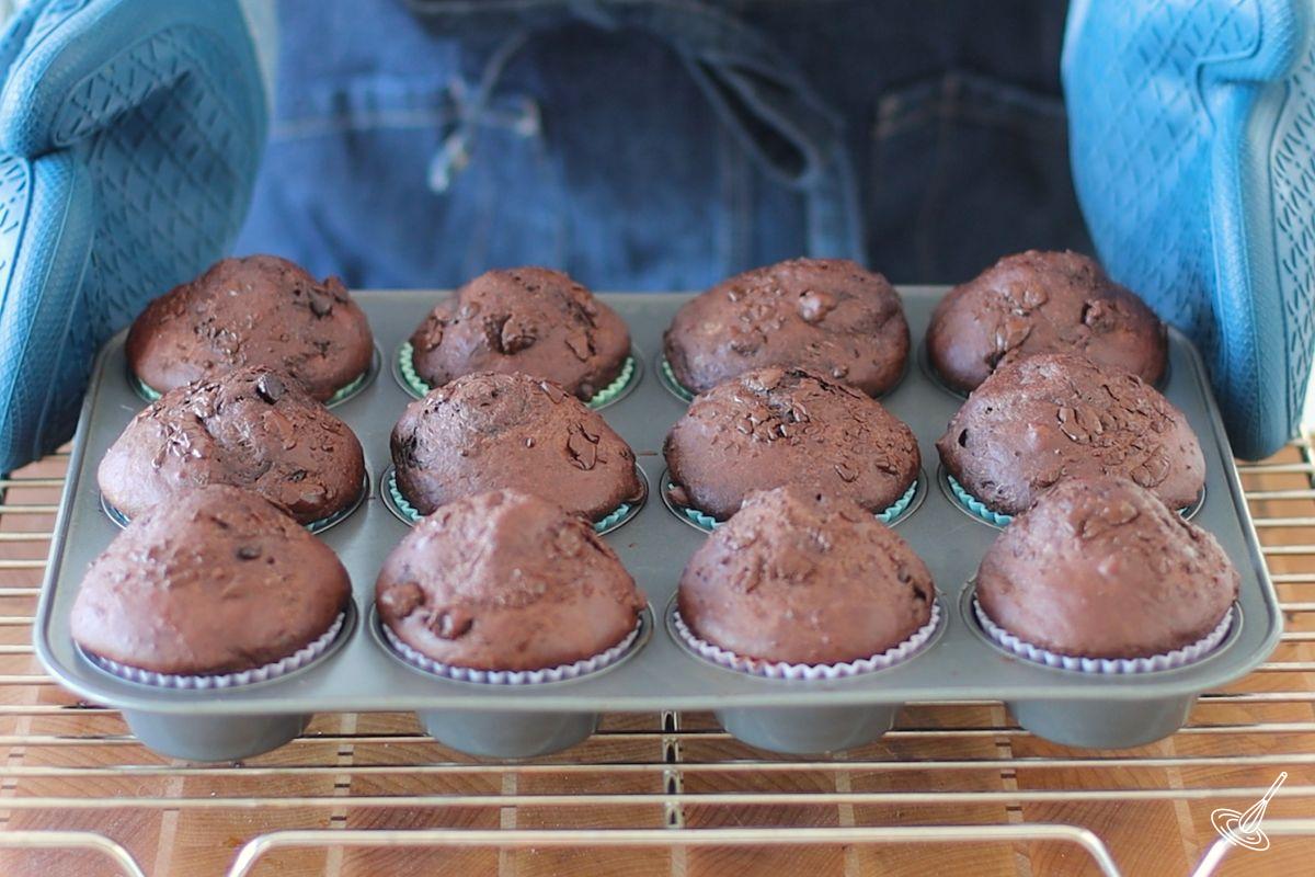 Someone placing a muffin baking tray of baked Chocolate cottage cheese muffins on a cooling rack. 