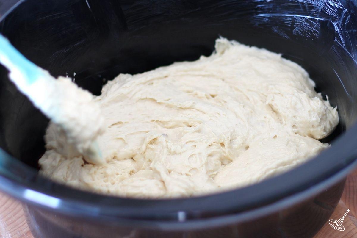 Someone spreading cake batter in a slow cooker.
