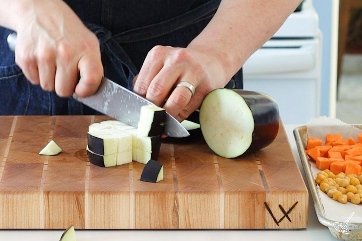 Someone cutting aubergine into ½ inch cubes.