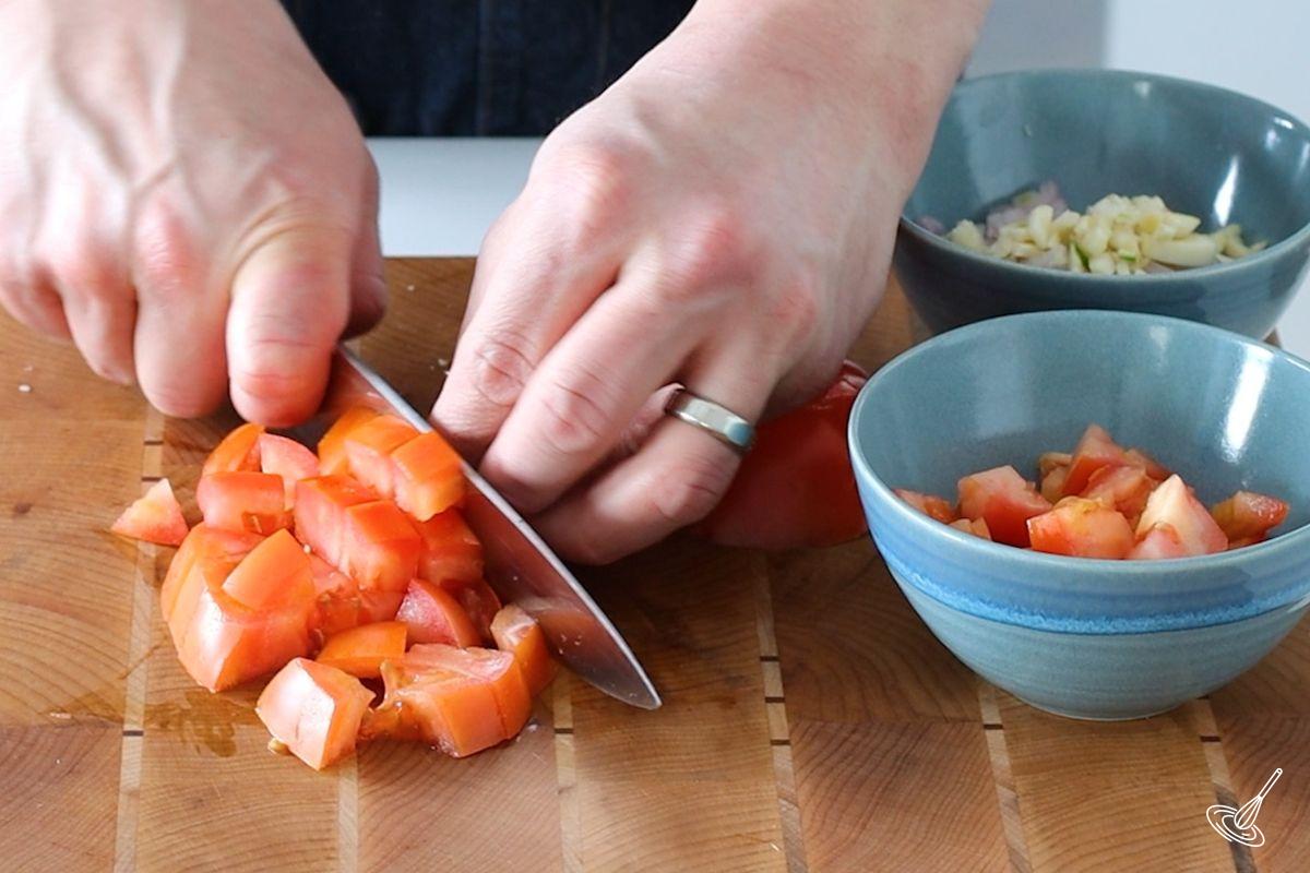 Someone cutting a tomato into cubes. 