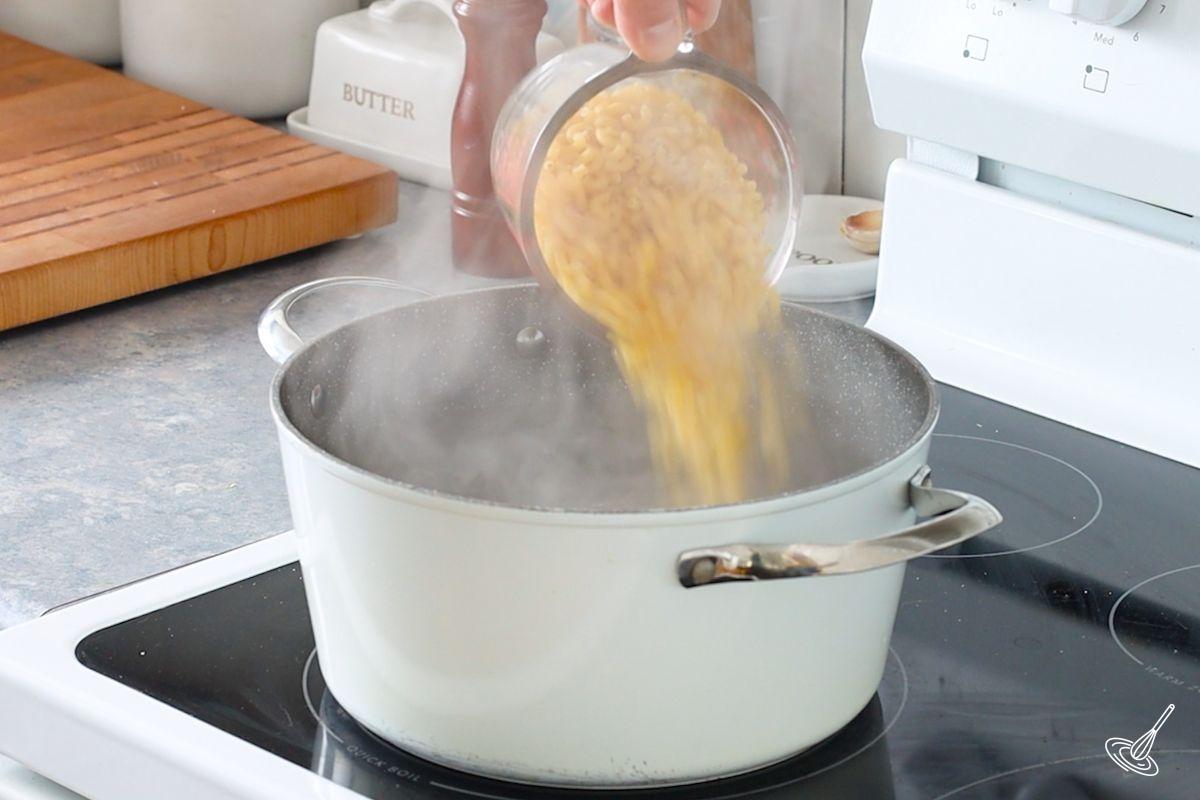 Someone adding pasta to a large pot of boiling water.