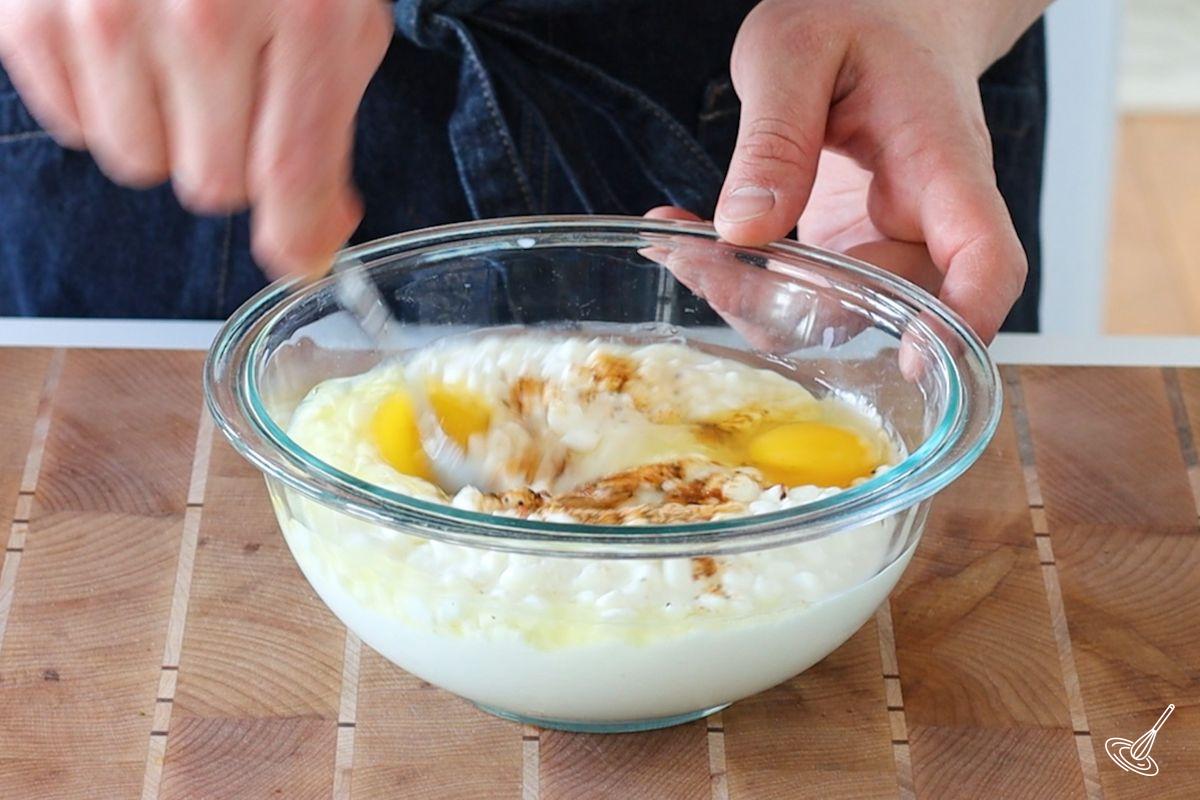 A medium bowl holding cottage cheese, eggs, and seasoning. 