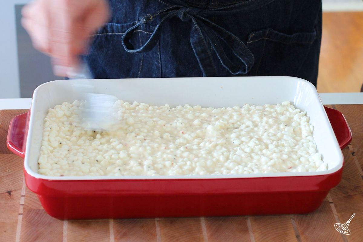 Someone spreading a cottage cheese mixture in a lasagna dish.