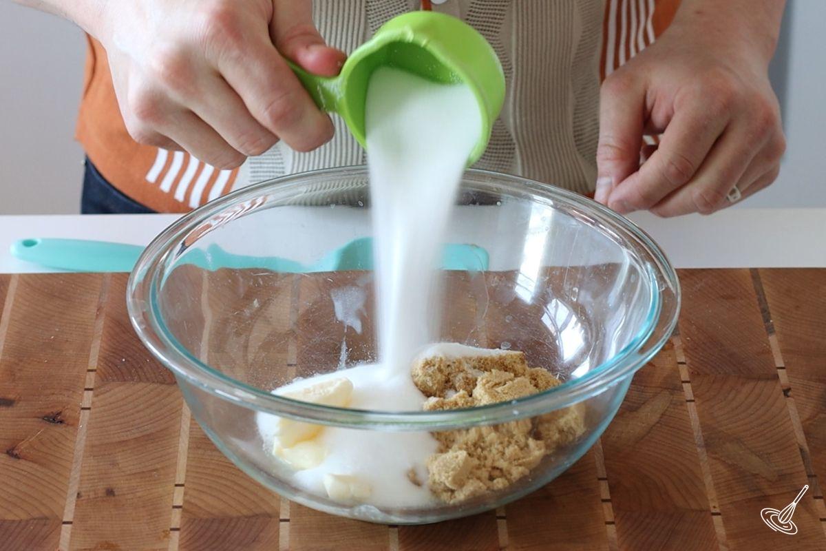 Someone combining sugar and butter in a large bowl.