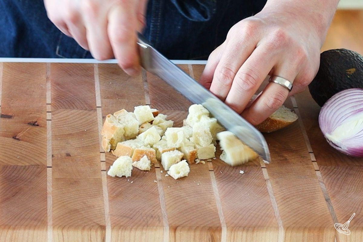 Someone cutting bread into cubes.