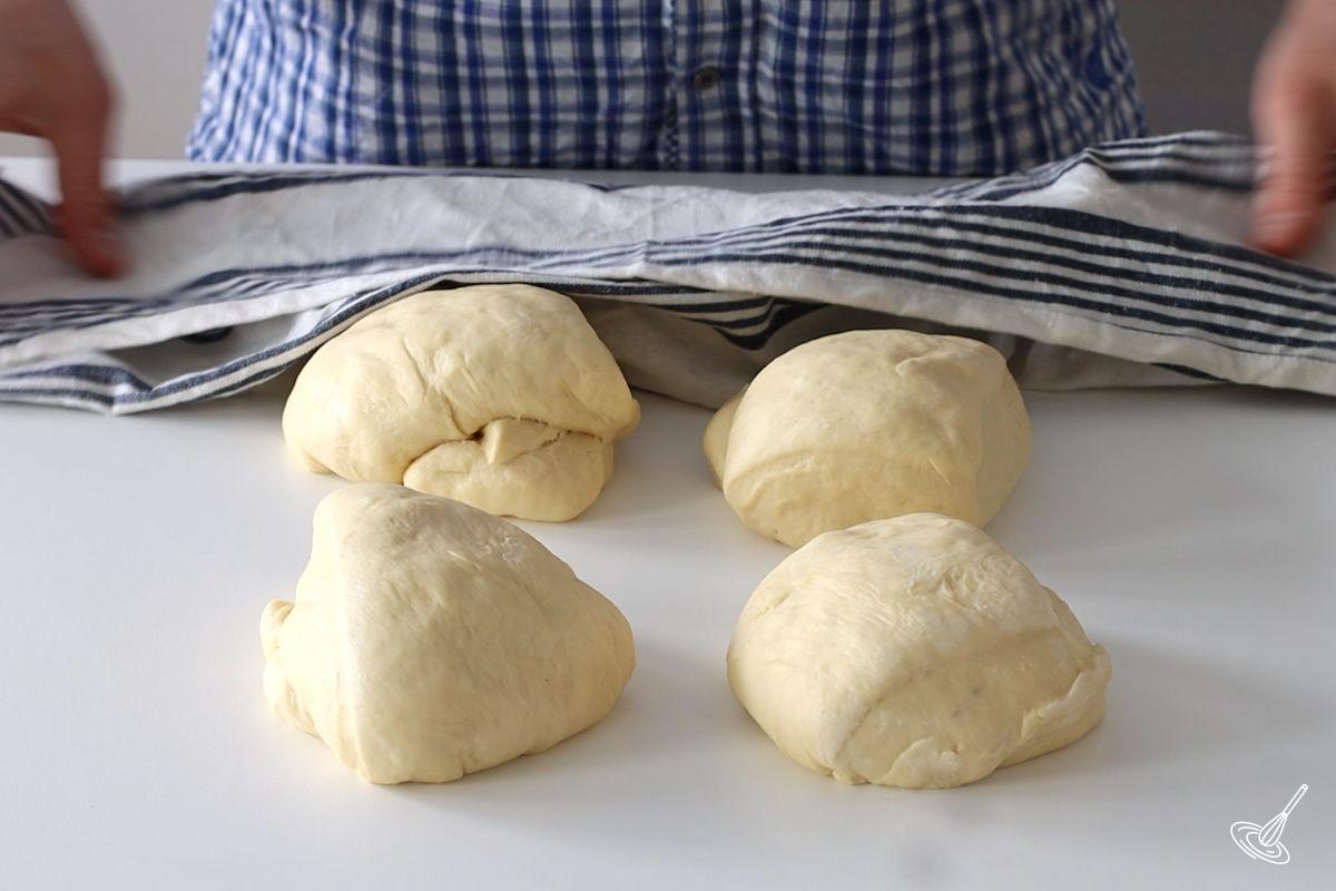 Four balls of dough resting on a kitchen counter.