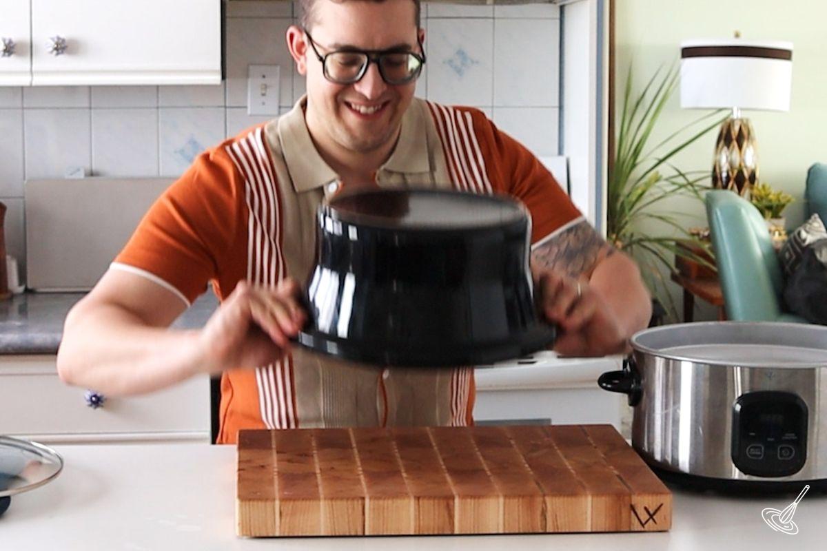 Someone flipping the crock over to flip the Crockpot Pineapple Upside Down Cake onto a plate. 