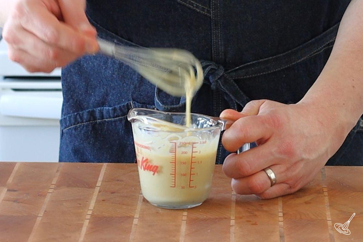 Someone whisking Tahini Dressing for the Roasted Sweet Potato and Aubergine Salad.