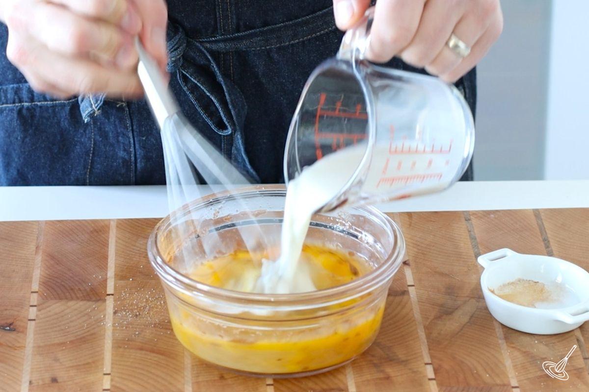 Someone whisking milk into a bowl of eggs.