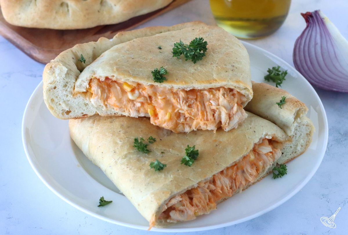 A buffalo turkey calzone cut in half on a plate.