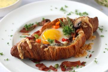 Croissant Egg Boat on a white plate.