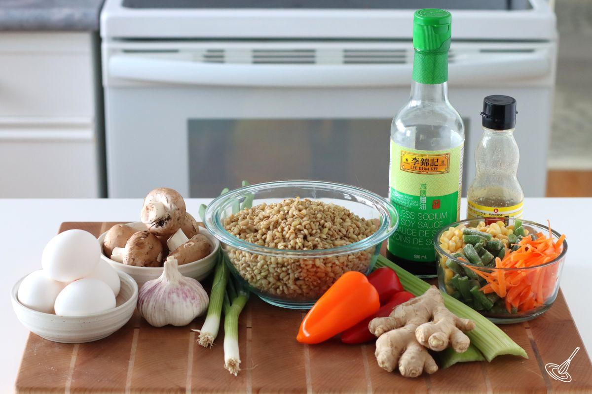 Ingredients on the kitchen counter, including cooked barley, eggs, and fresh vegetables.