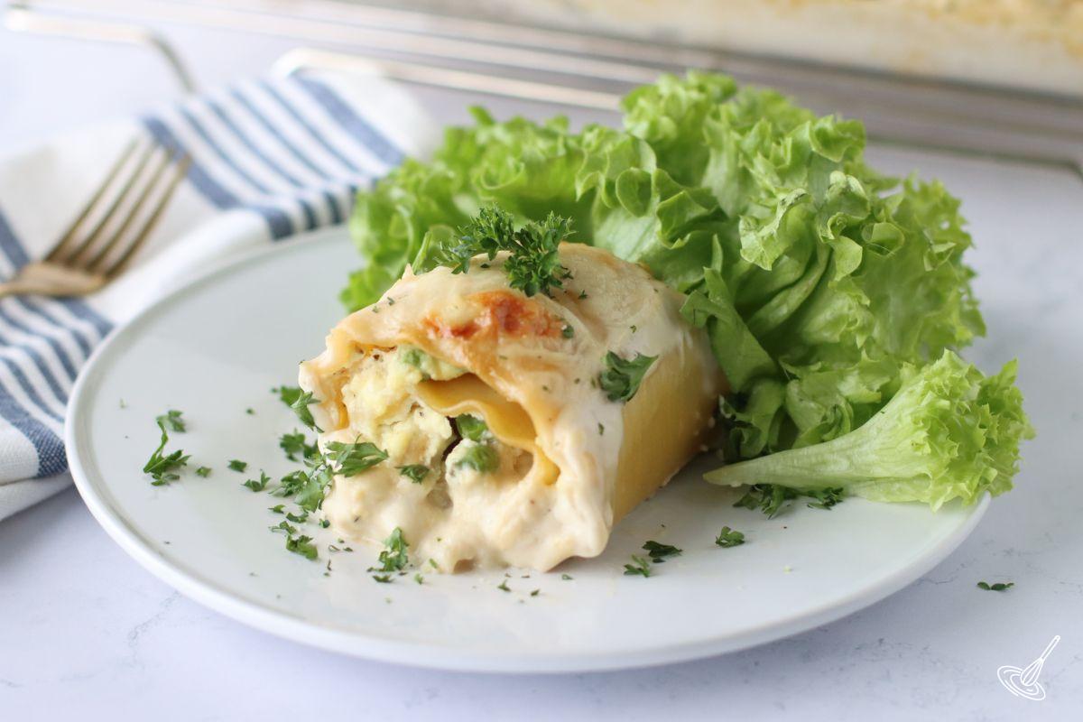 A Turkey Alfredo Lasagna Rollup on a plate with a green salad. 