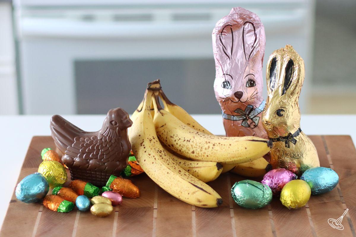 Easter Chocolate and a bunch of bananas on a wooden cutting board.