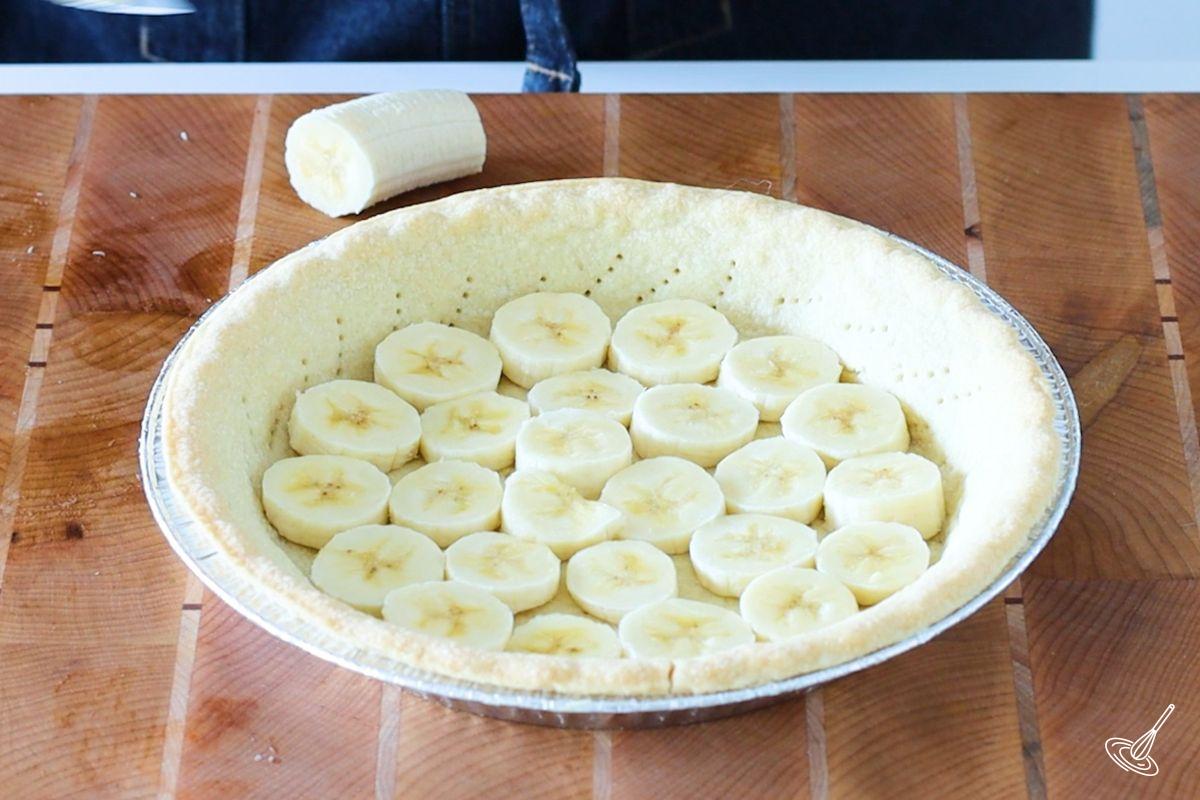A baked pie shell with slices of bananas on the bottom. 