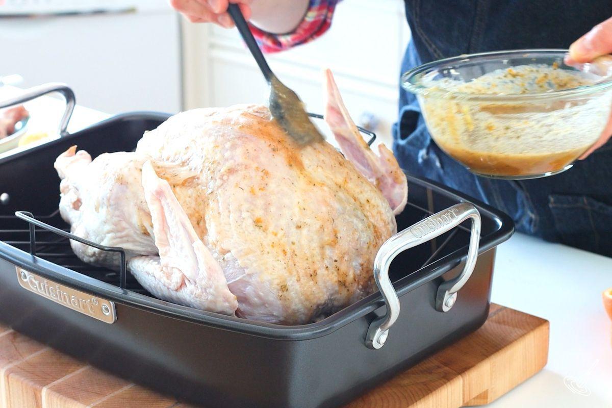 Someone brushing a turkey roast with maple orange glaze.