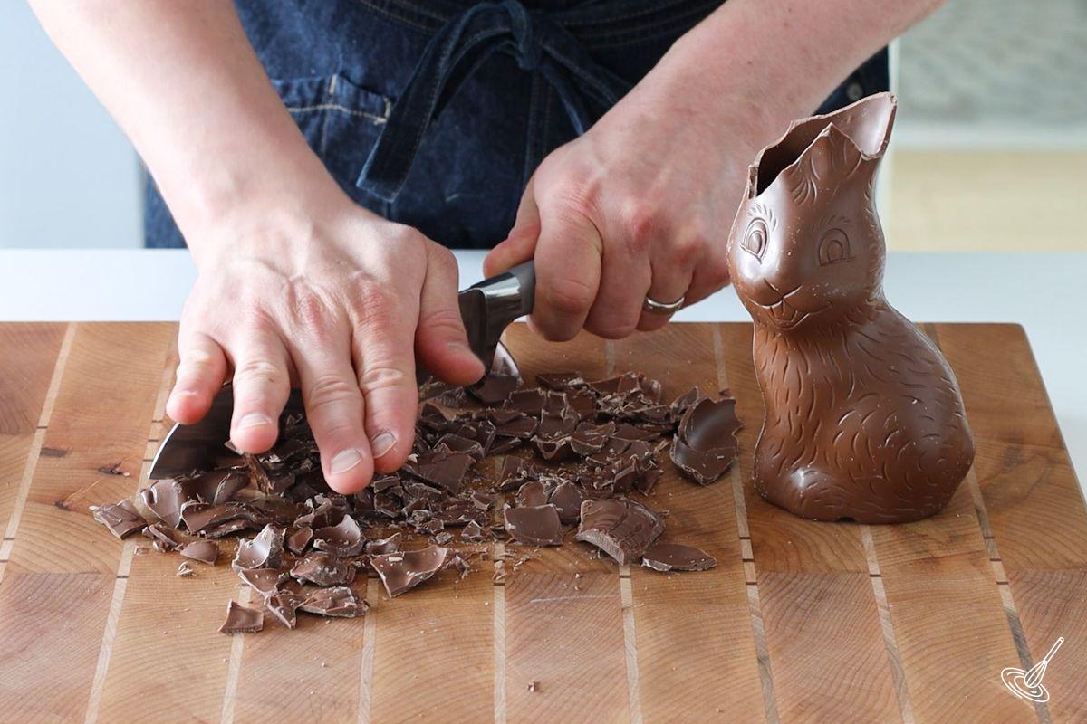 Someone using a large knife to chop an easter bunny into small pieces.