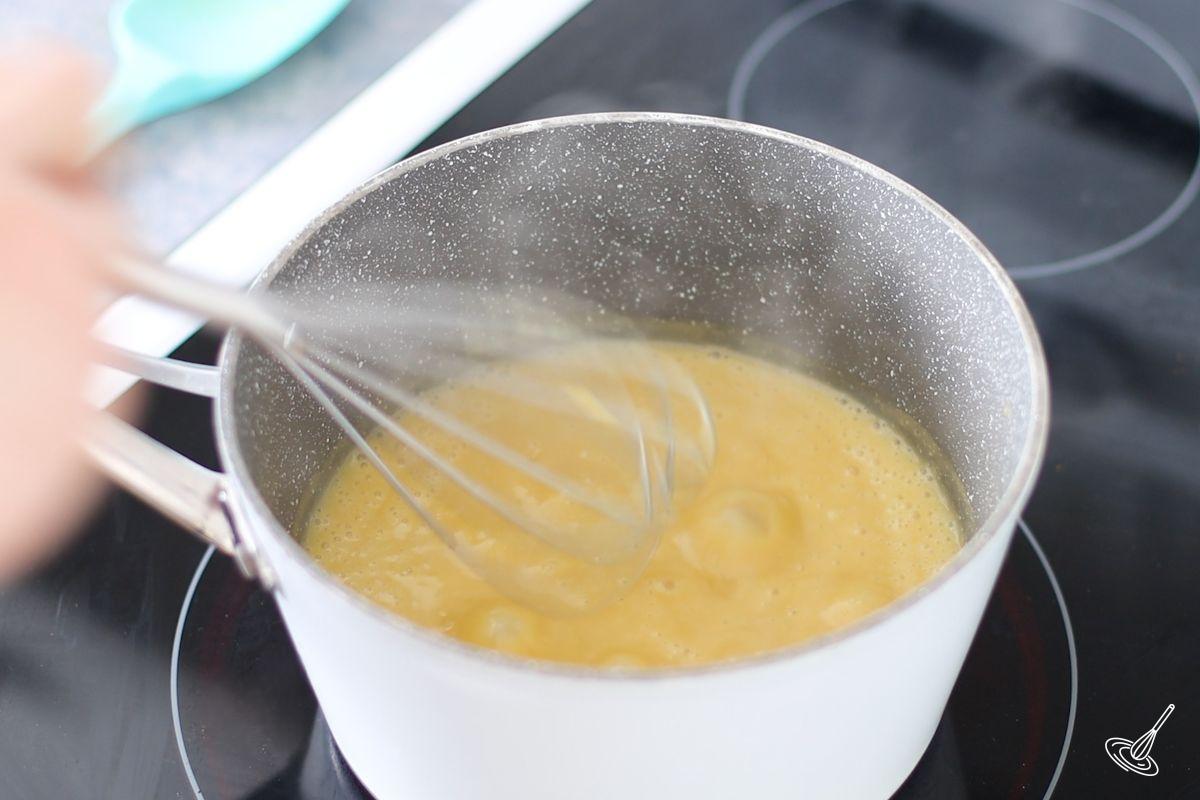 Someone cooking banana pudding in a medium saucepan.
