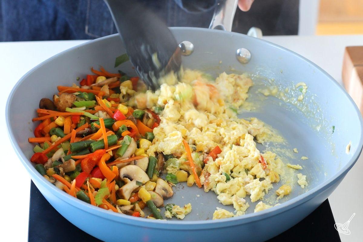 Someone stirring eggs while cooking until scrambled.
